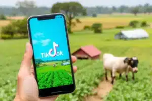 Fazenda com um smartphone exibindo o TikTok, representando marketing digital no agro.